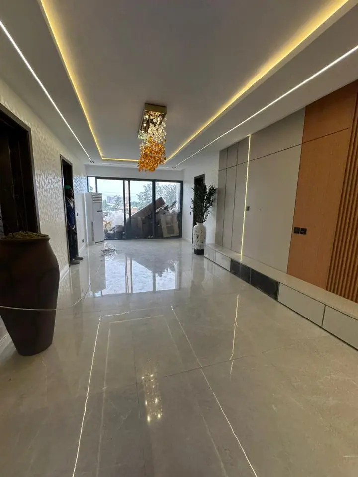 Hallway with LED cove lighting in the ceiling, a chandelier, polished floor tiles and a timber-slat wall panel