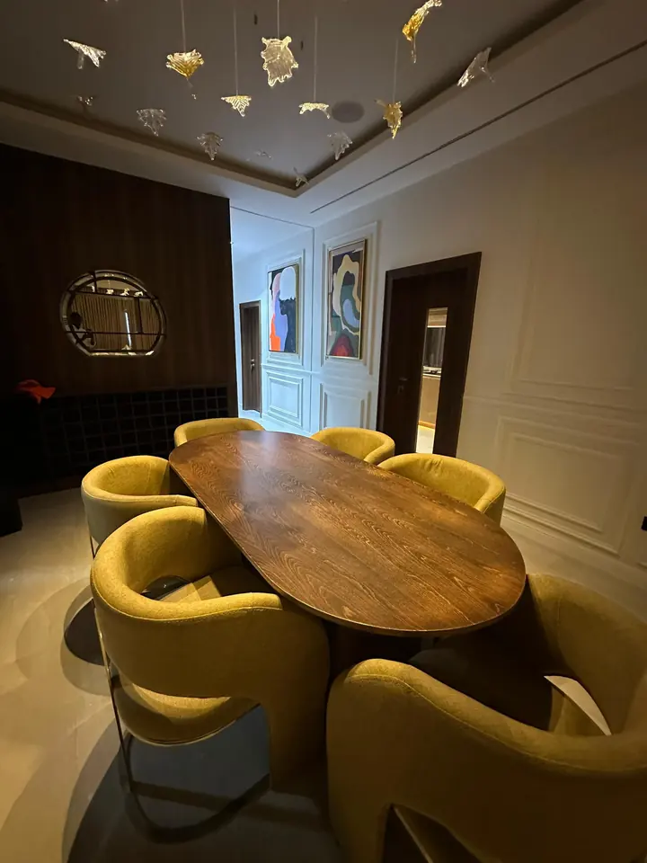 Dining area with an oval timber table, upholstered chairs and a suspended sculptural ceiling feature