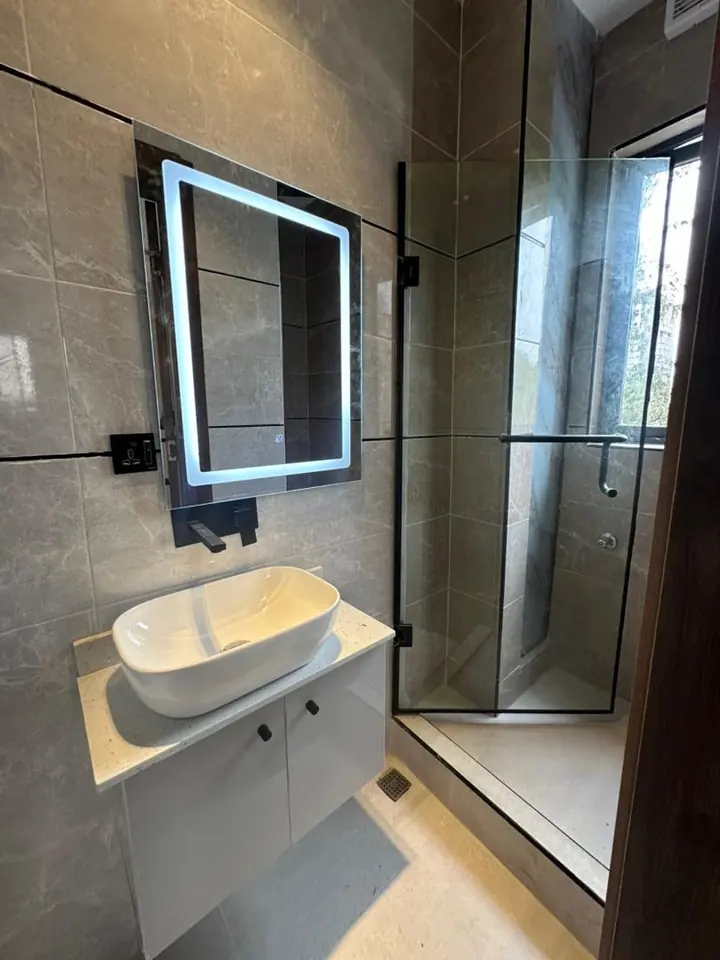 Bathroom with a floating vanity, backlit mirror and glass shower screen