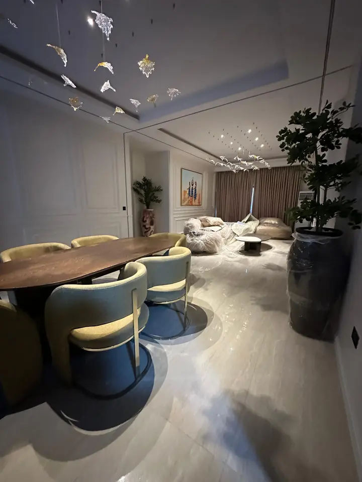 Open-plan living and dining space with wall panelling, a tray ceiling and polished floor tiles