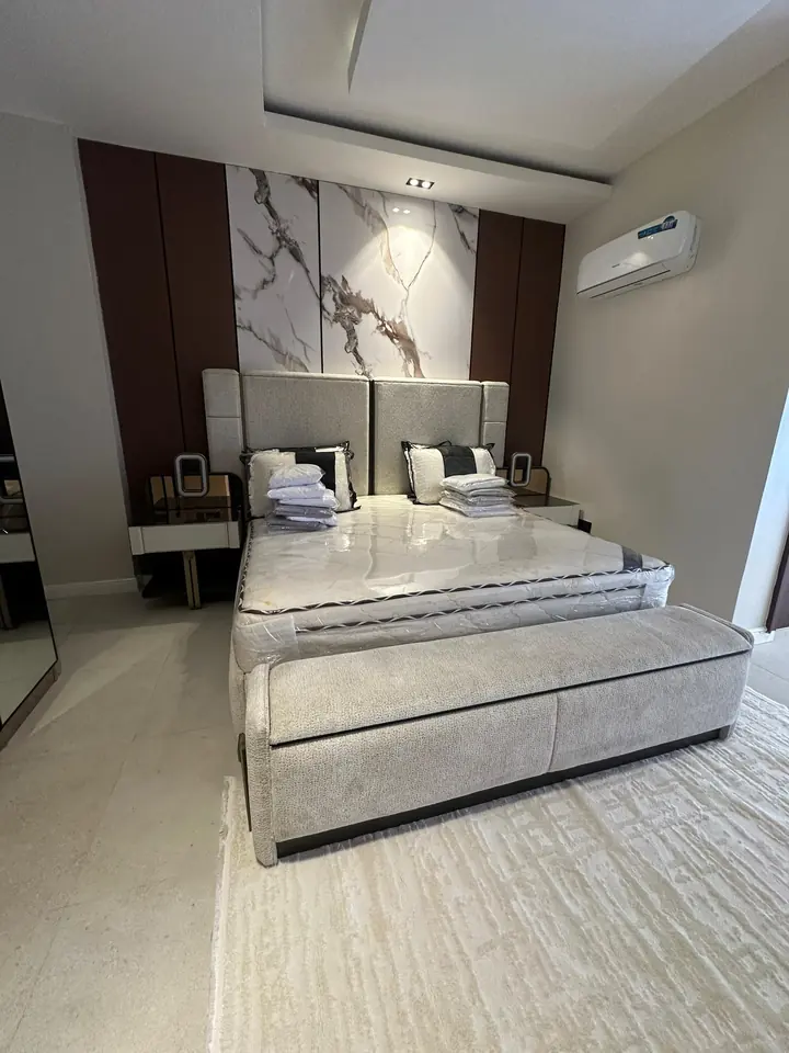 Bedroom with a marble-look feature wall and tray ceiling, seen from the side