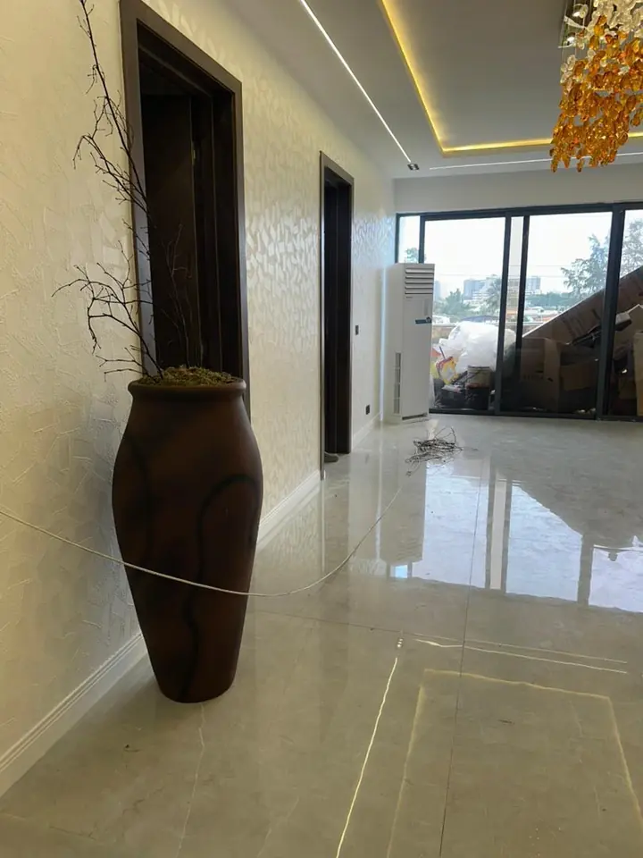 Hallway with a large floor vase, a textured wall and sliding glass doors at the far end